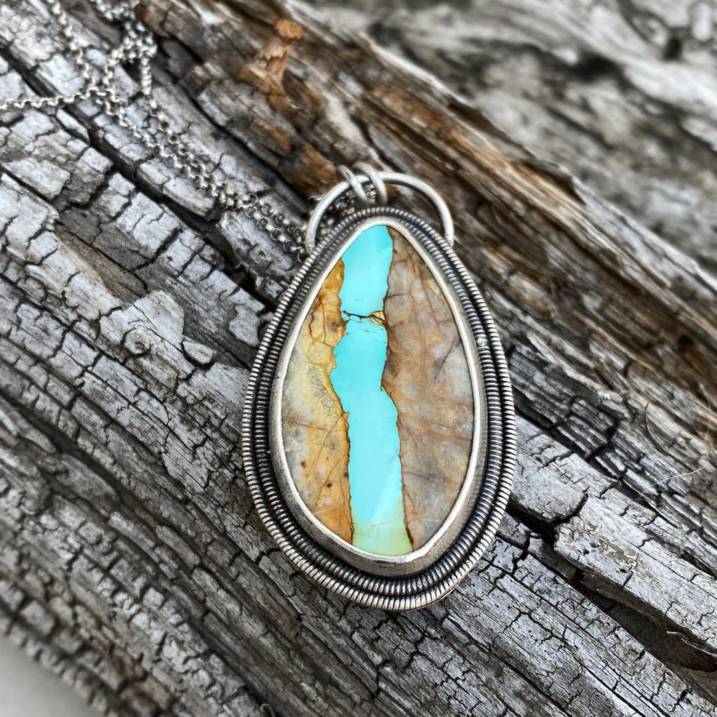 Pendant with a turquoise stone on a wooden surface