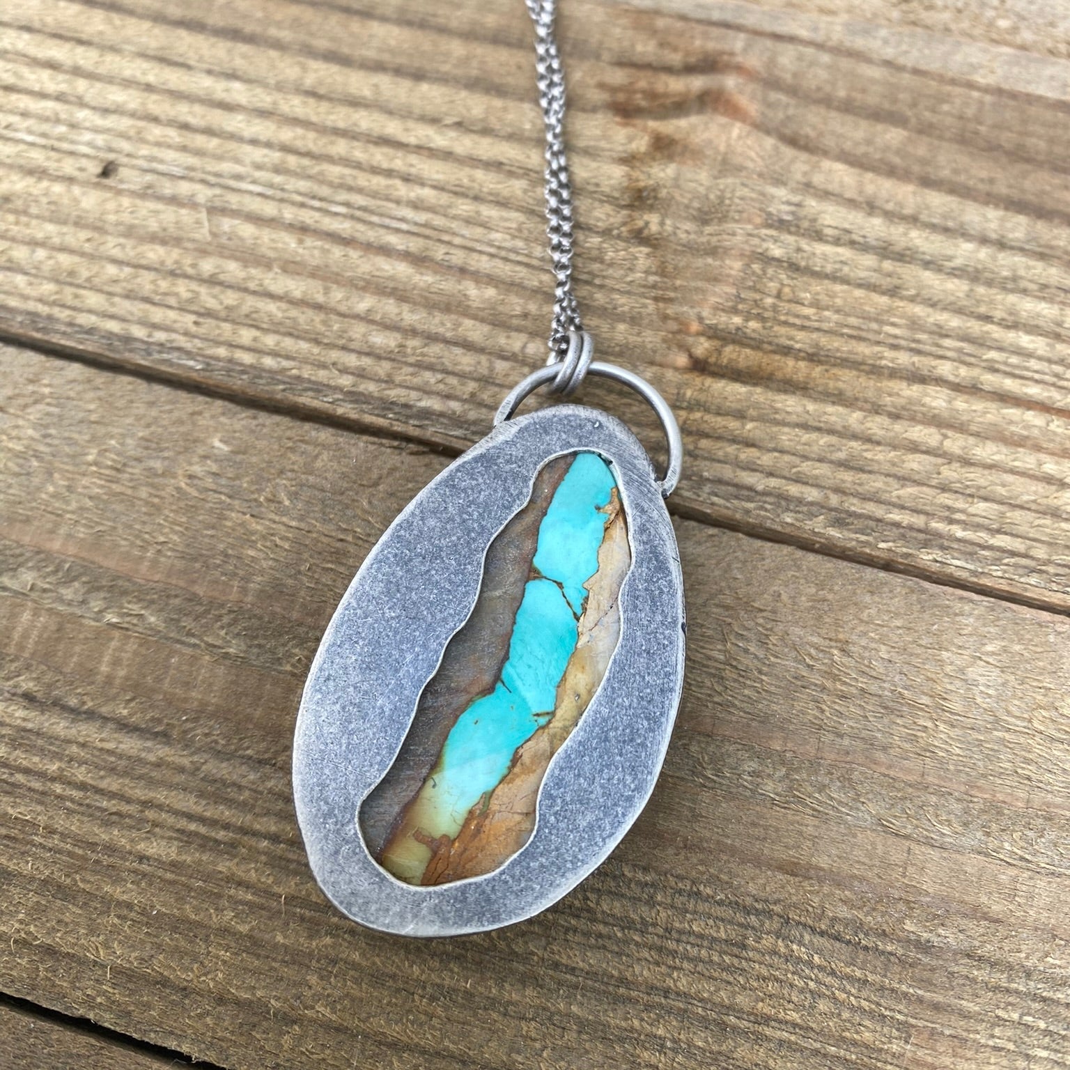 Necklace with a pendant featuring turquoise inlay on a wooden surface