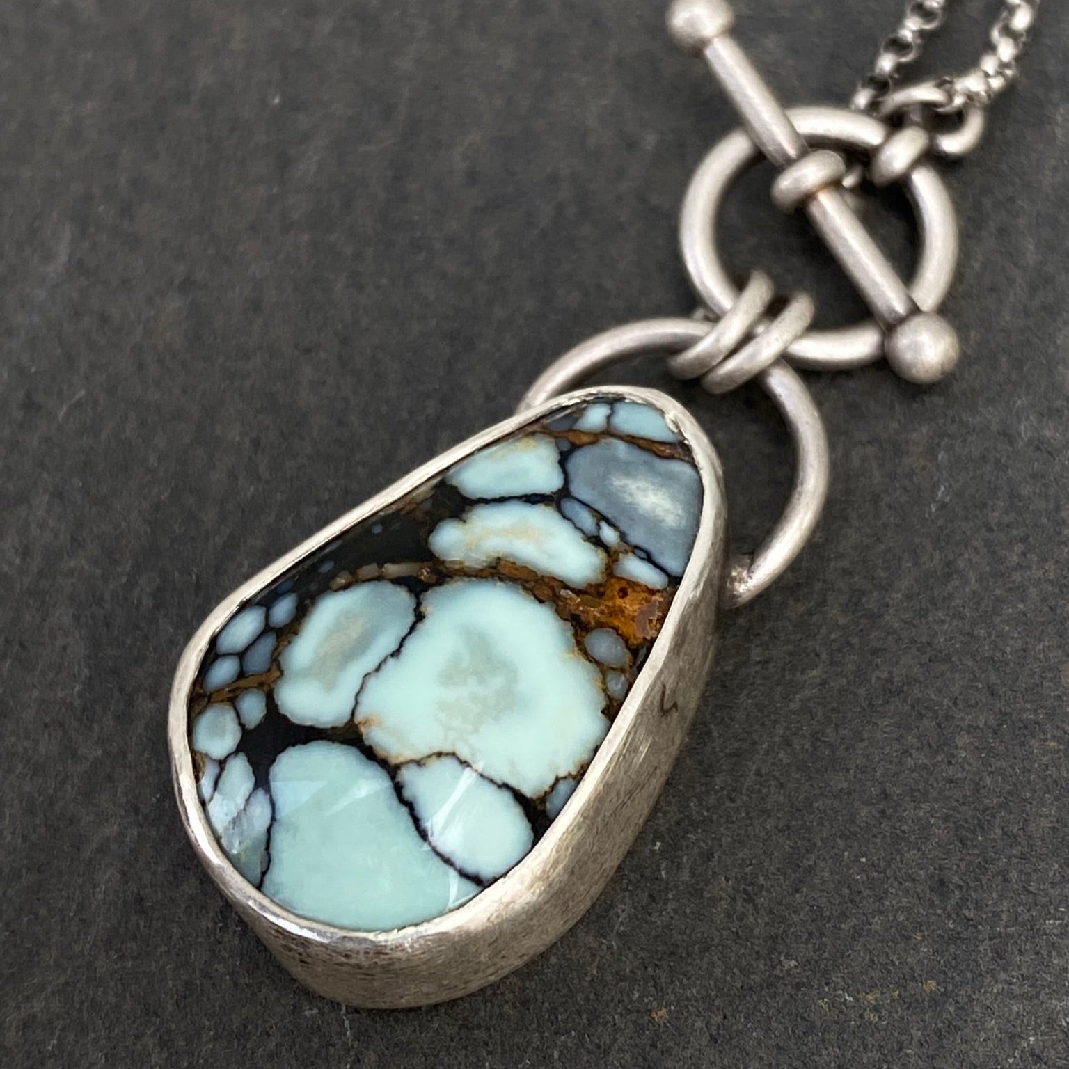 Necklace with a stone pendant on a dark surface